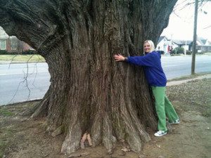 Janice Atkinson-Kiesel hugging a sassafras tree protected by a shotgun